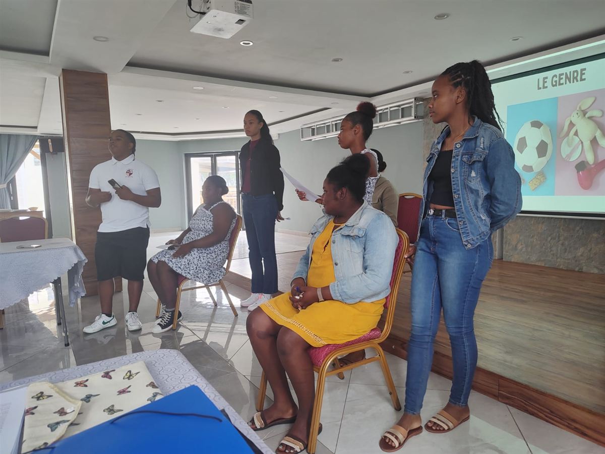 Formation des ambassadeurs à Rodrigues : des jeunes debout et assis devant un écran affichant « Le genre »