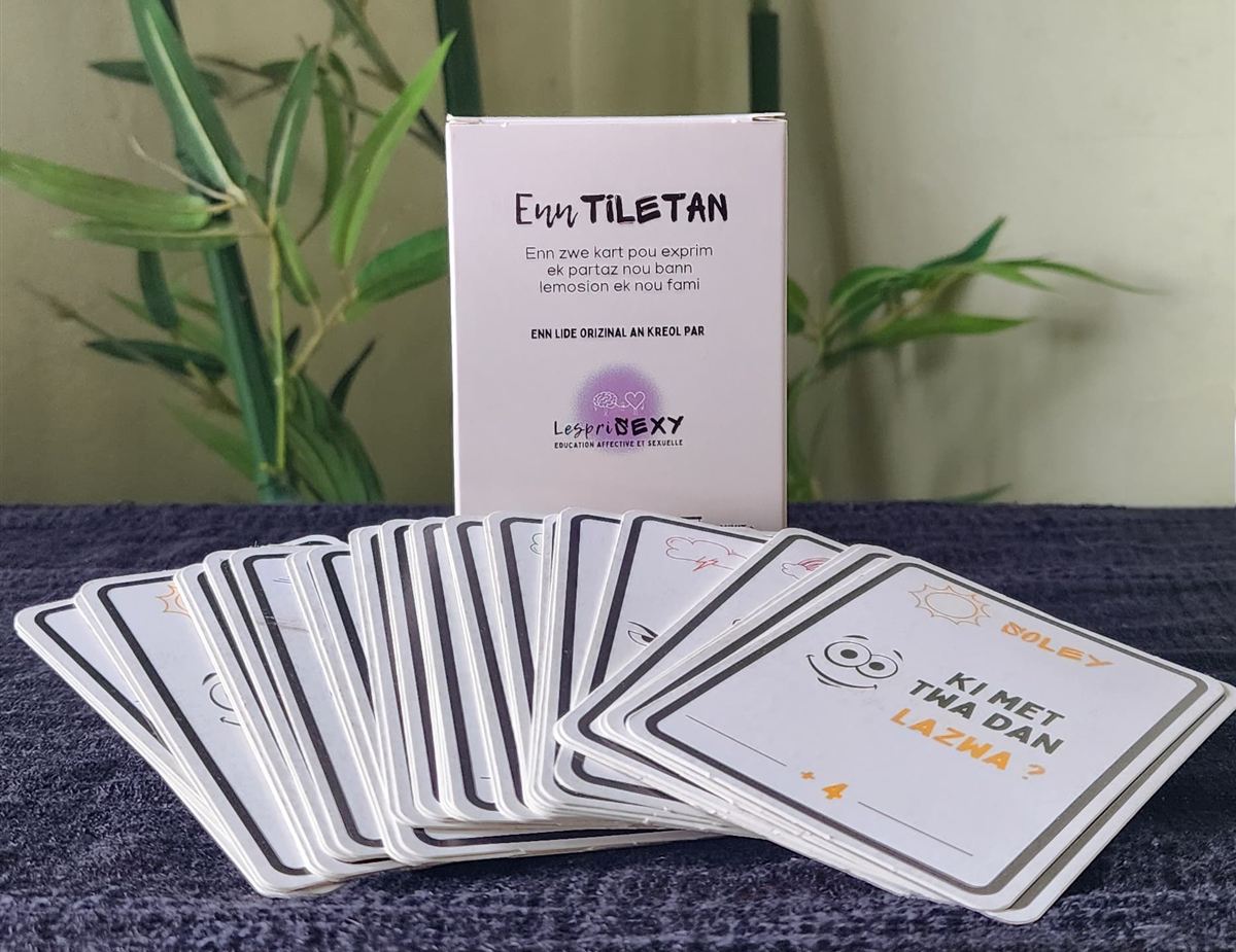 La boîte du jeu Enn tiletan, « Enn zwe kart pou exprim ek partaz nou bann lemosion ek nou fami », et ses cartes étalées en éventail