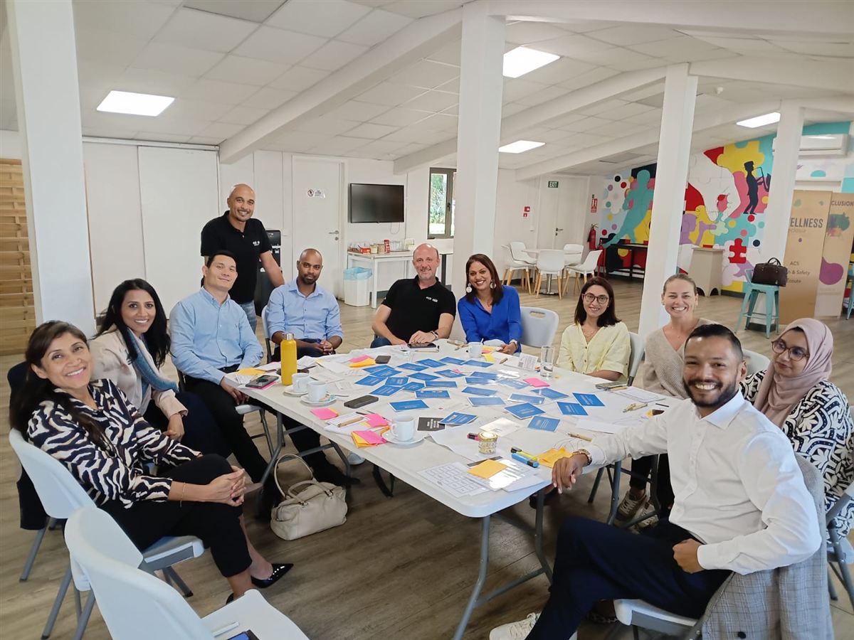 Une douzaine de collaborateurs réunis autour d'une grande table couverte de cartes de la Fresque de l'Équité, chez Eclosia