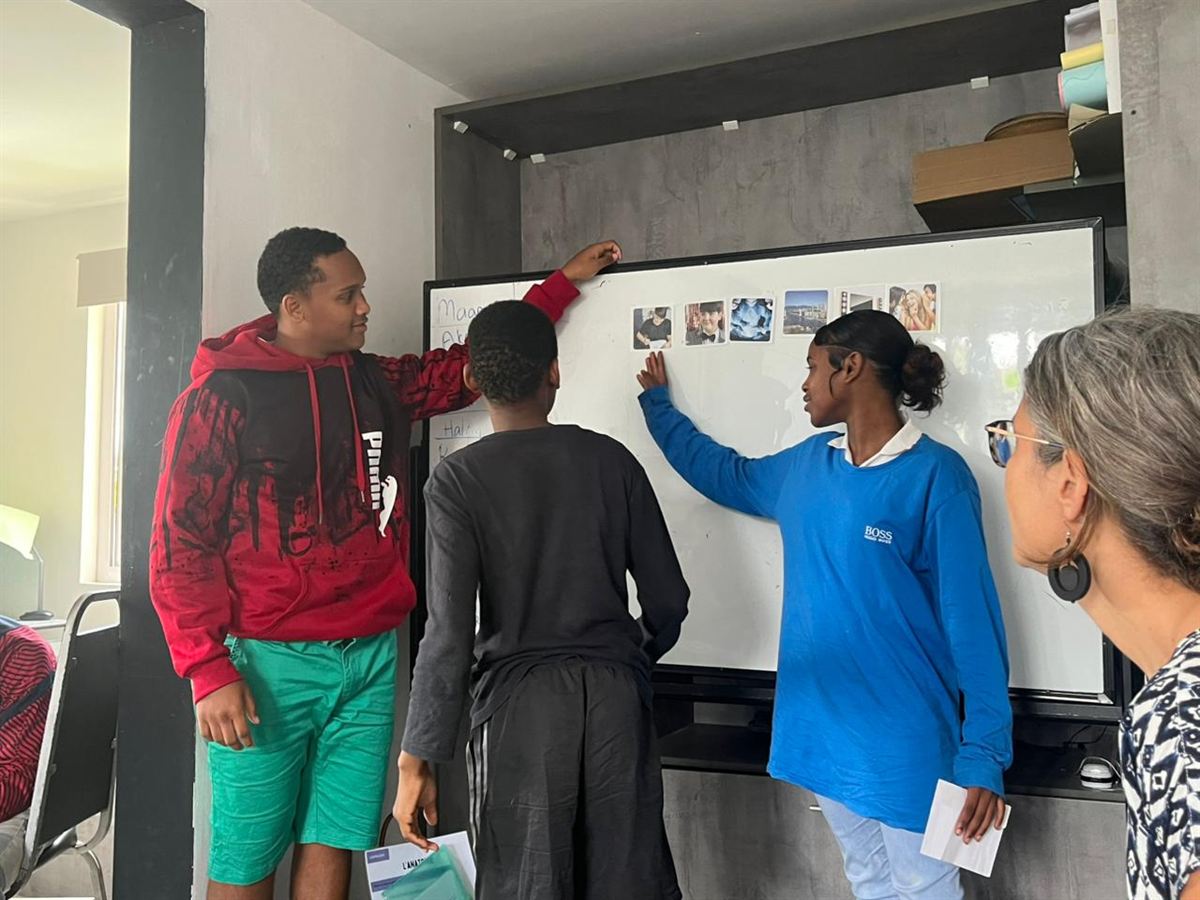 Atelier avec l'association Safire : trois adolescents placent des cartes photos sur un tableau blanc, sous le regard de l'animatrice